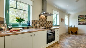 A kitchen with a large island, a stove, and a window with a view of trees.