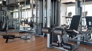 Ett gym med olika typer av träningsutrustning, inklusive styrketräningsmaskiner och lösa vikter.