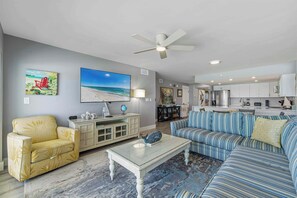 A living room with a sofa, armchair, coffee table, and a TV. - Vibrant 3BR gulf front condo with beach access (Okaloosa Island)
