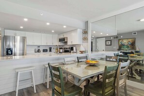 A modern kitchen with white cabinets, stainless steel appliances, and a large island with seating. - Vibrant 3BR gulf front condo with beach access (Okaloosa Island)