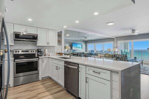 A modern kitchen with stainless steel appliances, a dishwasher, and a large island. - Vibrant 3BR gulf front condo with beach access (Okaloosa Island)