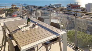 A balcony with a table, a bottle of champagne, and a bowl of chocolates. - Penthouse With sea and Lagoon View (Lignano Sabbiadoro)