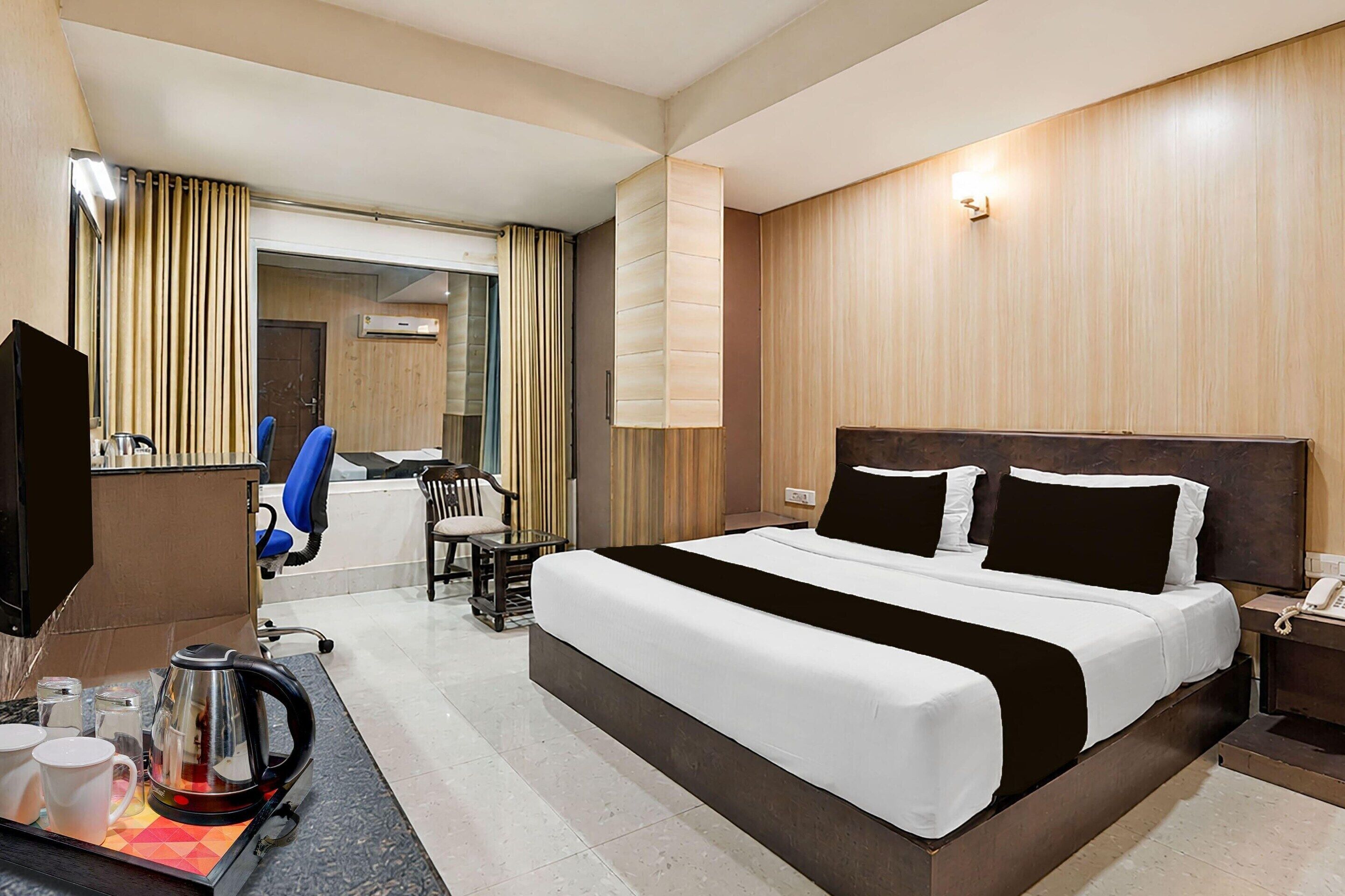 A hotel room with a large bed, a desk with a telephone, a coffee maker, and a chair.