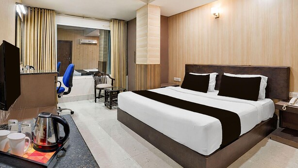 A hotel room with a large bed, a desk with a telephone, a coffee maker, and a chair. - Deluxe Twin Room Gold Stone Comfort (Dehradun)