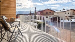 Un balcon avec vue sur les montagnes, un mur en bois et une balustrade blanche.