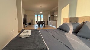 Ein Schlafzimmer mit Bett, Nachttisch und Blick auf einen Essbereich und eine Küche.