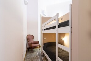 A bunk bed room with a chair and a wall-mounted air conditioner. - Elegant apartment of 66 sqm can accommodate up to 4 people, located on the third floor of a period building with a lift (4 steps to access). The property is located in the historic center of Livorno, just 3 minutes walk from the Duomo and a short walk fr (Livorno)