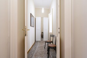 Ein Flur mit Fliesenboden, einer Tür mit goldener Griff und einem gerahmten Bild an der Wand.