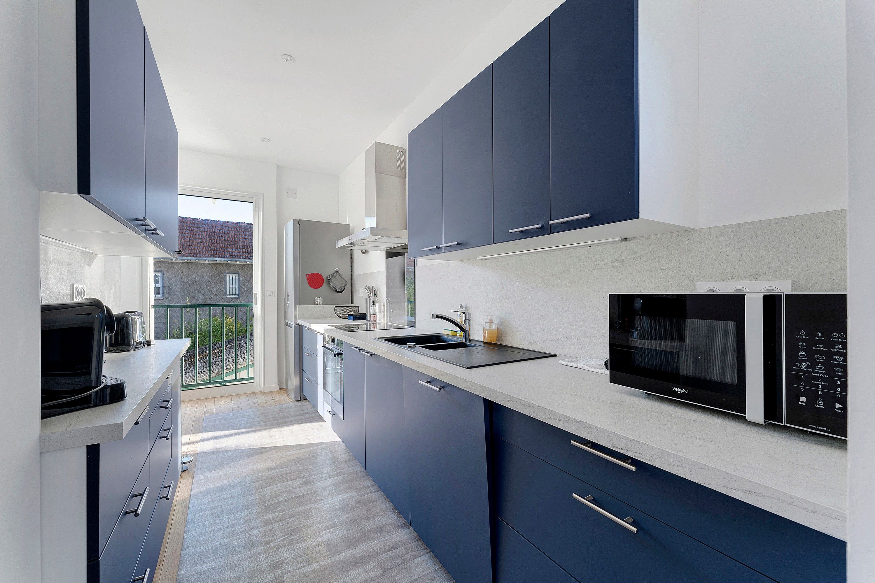 Een moderne keuken met donkerblauwe kastjes, een magnetron en een inbouwoven.