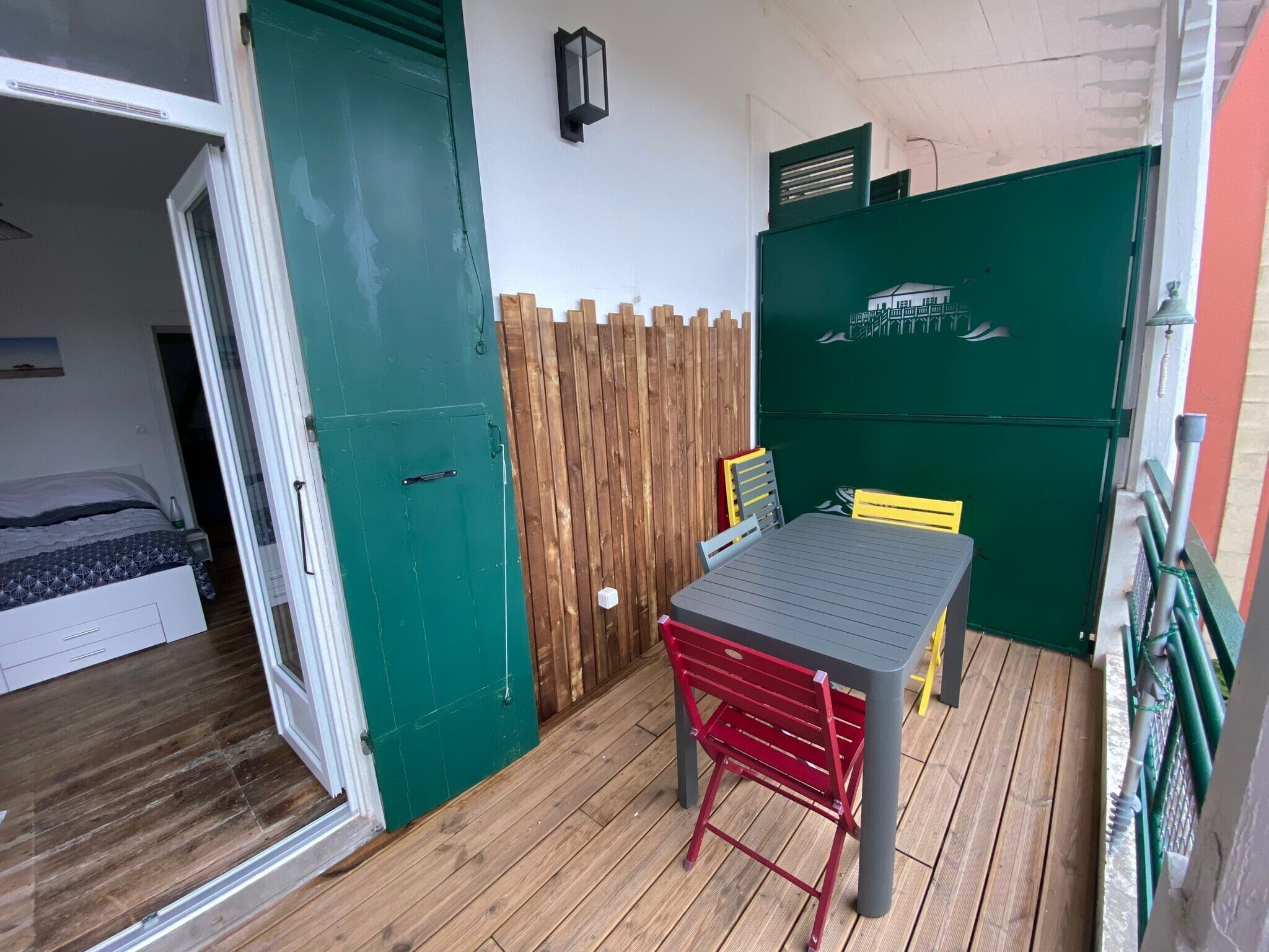 A room with a bed, a table with chairs, a wooden fence, and a green door.