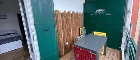 A room with a bed, a table with chairs, a wooden fence, and a green door.