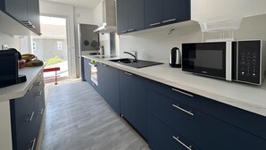 Una cocina moderna con armarios oscuros, encimera de acero inoxidable y microondas integrado.
