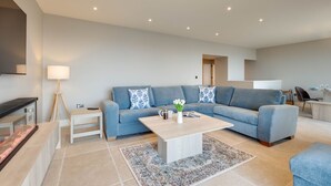 Un salon moderne avec un canapé, une table basse, une lampe et une petite table d’appoint.