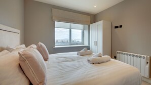 Une chambre avec un grand lit, une fenêtre donnant sur un beau paysage, un radiateur et une armoire.