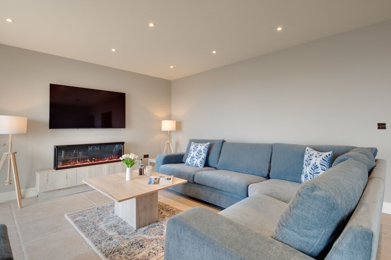 A modern living room with a fireplace, a sofa, a coffee table, and a TV mounted on the wall.