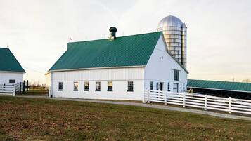 A white barn with a green roof and a silo.