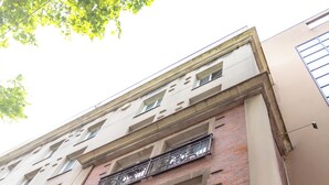 En bygning med flere etager, murstensfacade, flere altaner med smedejernsrækværk og forskellige vinduesdesigns.