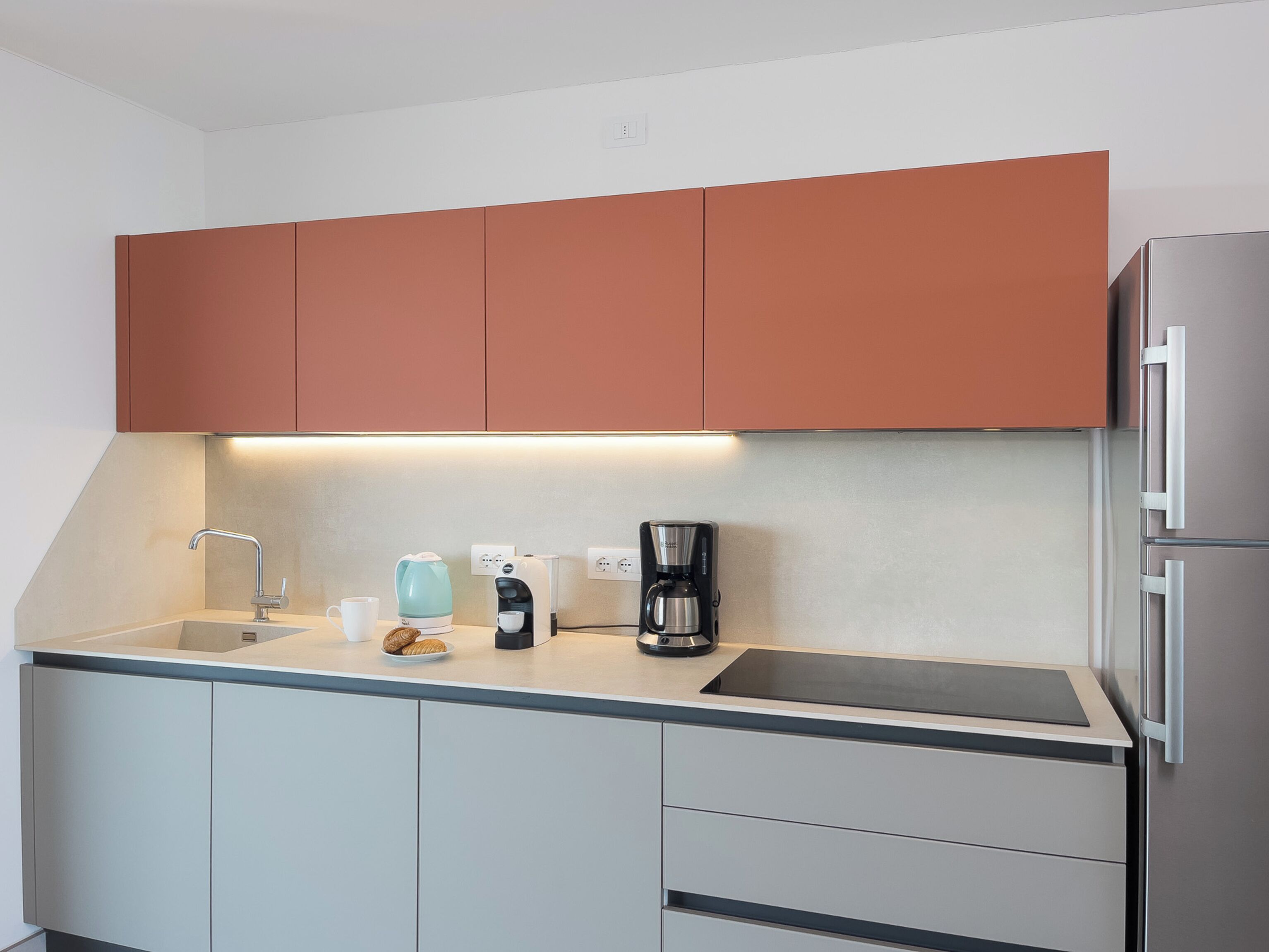 A modern kitchen with a built-in oven, a coffee maker, and a sink.