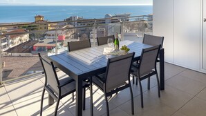 Een balkon met een tafel gedekt voor twee personen, een fles champagne en een schaal druiven.
