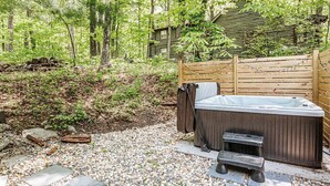 Een hottub in een bebost gebied met een houten terras en treden ernaartoe.