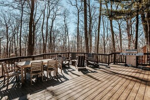 Une terrasse en bois avec une table et des chaises, entourée d’arbres.
