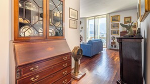 A room with a wooden cabinet, a blue sofa, and a view of the outdoors. - Miraluna – Lake Como View Balcony (Griante)