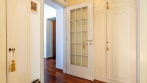 A hallway with a white door with glass panels, wooden flooring, and a white wall with a picture frame. - Miraluna – Lake Como View Balcony (Griante)