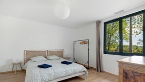 Une chambre à coucher comprenant un lit, une table de chevet, une armoire, une fenêtre avec vue et un luminaire suspendu.