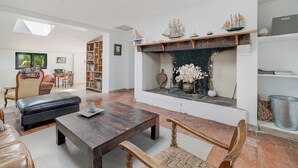 Un salon avec une cheminée, un canapé en cuir, une table basse en bois et une bibliothèque.