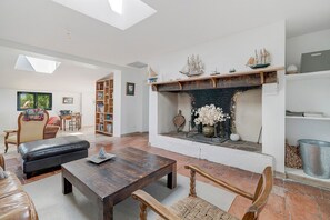 A living room with a fireplace, leather sofa, wooden coffee table, and a bookshelf.