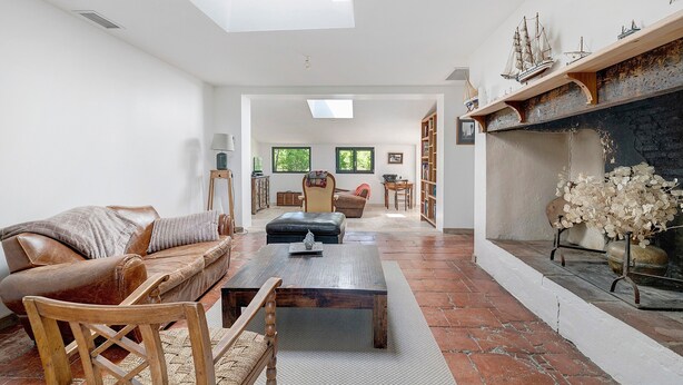 Un salon spacieux avec un canapé en cuir, une table basse en bois et une cheminée ornée de maquettes de bateaux.