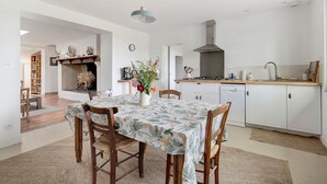 Une cuisine moderne avec des armoires blanches, une cuisinière encastrée et un luminaire suspendu.