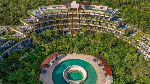 Ein kreisförmiger Pool, umgeben von einem Resort mit mehreren Etagen und Balkonen.