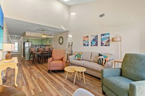 A living room with a sofa, armchairs, a dining area, and a kitchen in the background. - Coastal Shores B3- Amazing Oceanfront 2 Bedroom (North Myrtle Beach)