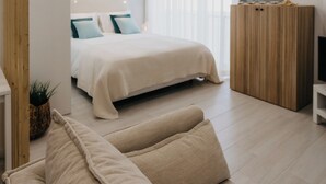 Een moderne slaapkamer met een bed, een houten garderobe, een sofa en een kleine plant.