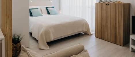Un dormitorio moderno con una cama, un armario de madera, un sofá y una planta pequeña.