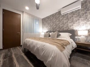 A bedroom with a bed, a nightstand, an air conditioning unit, a door, and a window with curtains. - Paramar Black 2BR Apt / Two Pools-Sauna-Concierg (Tulum)