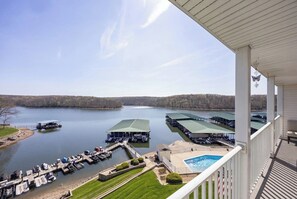 A lakeside property with a dock, a swimming pool, and a covered outdoor seating area. - Waterfront Osage Beach Condo w/ Boat Slip & Pool Access (Osage Beach)