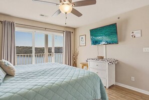 A bedroom with a bed, a ceiling fan, a dresser, a window with curtains, and a painting on the wall. - Waterfront Osage Beach Condo w/ Boat Slip & Pool Access (Osage Beach)