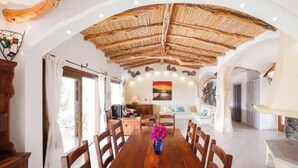 A dining area with a wooden table, chairs, and a vase of flowers. - Villa Giulia: a charming retreat among the rocks of the Costa Smeralda (Arzachena)