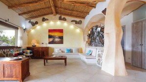 Un amplio salón con una pared de piedra, un cuadro, un sofá, una mesa de centro y un mueble de madera.