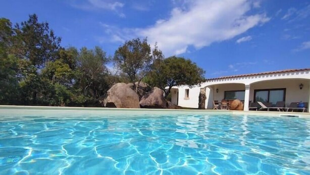 A clear swimming pool with a white building in the background. - Villa Giulia: a charming retreat among the rocks of the Costa Smeralda (Arzachena)