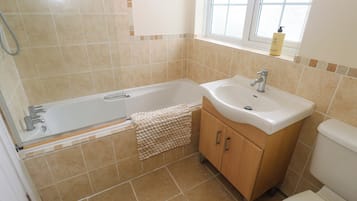 Un baño con bañera, lavamanos e inodoro.
