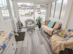 Una veranda con vista su case, una sedia in vimini, un divano e un tavolo con una tovaglia colorata.