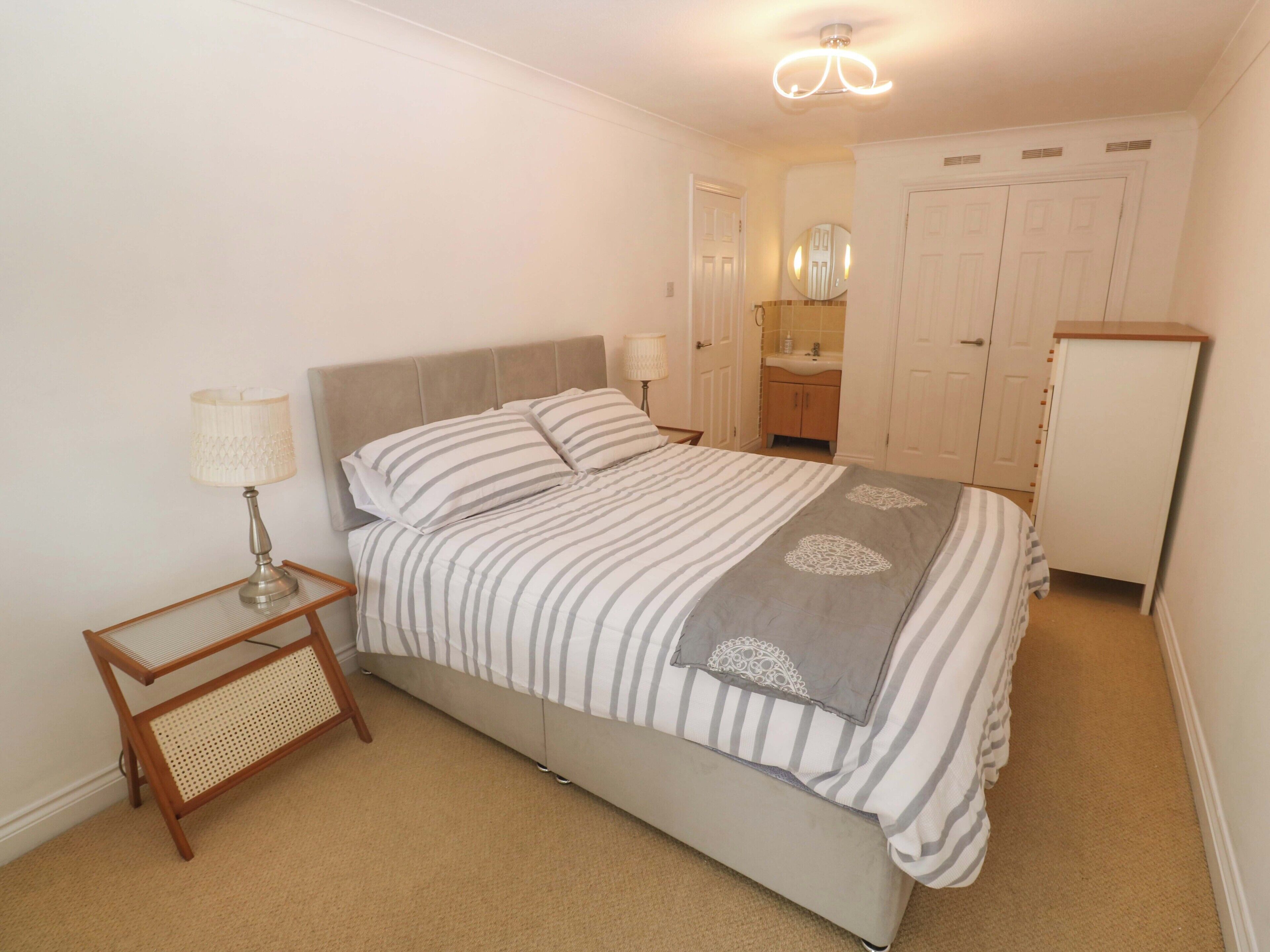A bedroom with a bed, bedside table, lamp, and a wardrobe.