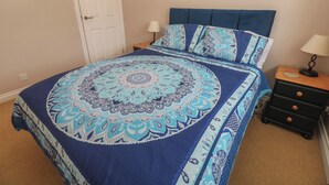 Une chambre à coucher avec un lit, des tables de chevet, une lampe et une porte.