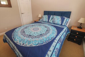 A bedroom with a bed, nightstands, a lamp, and a door.