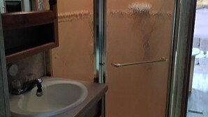 Kylpyhuone, jossa on pesuallas, peili ja lasinen suihkuseinä.