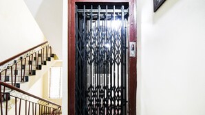 A staircase with a metal railing leading to a door with a metal gate. - Deluxe Hotel Okasu Railway Station (Raipur)