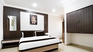 A bedroom with a bed, a wardrobe, a painting, and a mirror. - Deluxe Hotel Okasu Railway Station (Raipur)